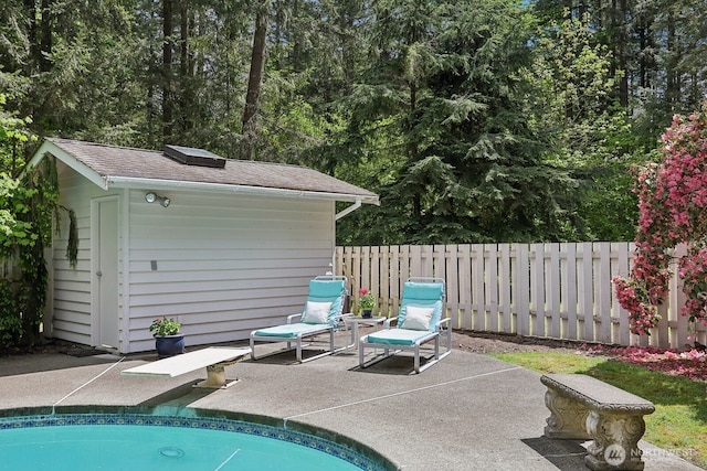 view of swimming pool featuring a patio, fence, an outbuilding, and a storage unit