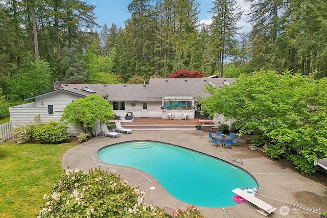 swimming pool with a wooden deck, fence, and a patio