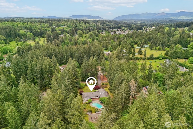 drone / aerial view of a mountainous background, a heavily wooded area, and a pool