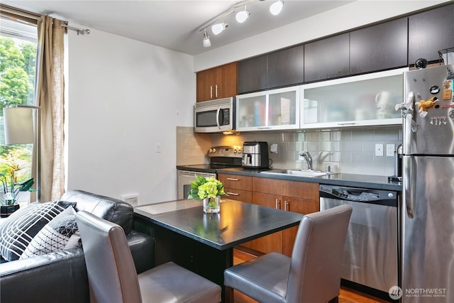 4547 8th Ave NE Unit 308, Seattle, WA 98105 - kitchen with decorative backsplash, a sink, a breakfast bar, dark countertops, and stainless steel appliances