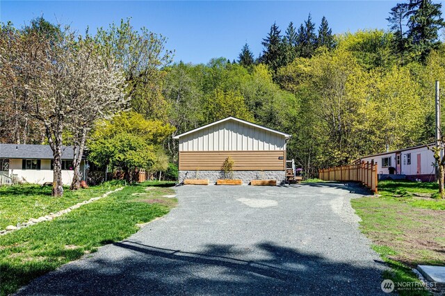 view of front facade featuring driveway and a view of trees