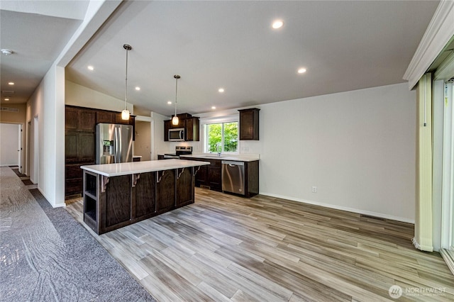 kitchen with dark brown cabinetry, stainless steel appliances, a center island, and light countertops