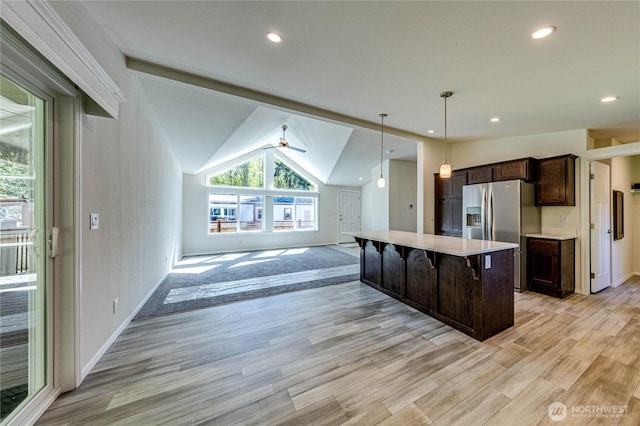 kitchen featuring light wood-style floors, dark brown cabinetry, open floor plan, a kitchen bar, and stainless steel fridge with ice dispenser