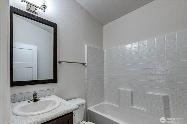 bathroom with toilet, vanity, and  shower combination