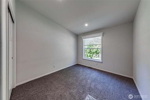 spare room featuring recessed lighting, dark carpet, vaulted ceiling, and baseboards