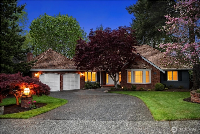 view of front of home featuring an attached garage, a front lawn, driveway, and a chimney