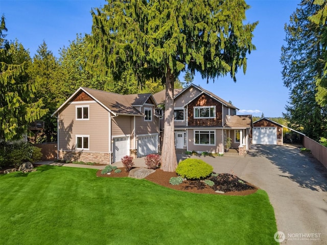 craftsman-style house with fence, driveway, a front lawn, and stone siding