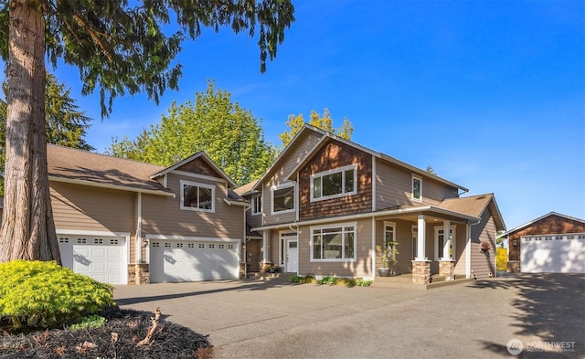 craftsman inspired home with a porch, driveway, and stone siding
