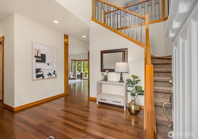 interior space featuring recessed lighting, baseboards, wood finished floors, and a towering ceiling