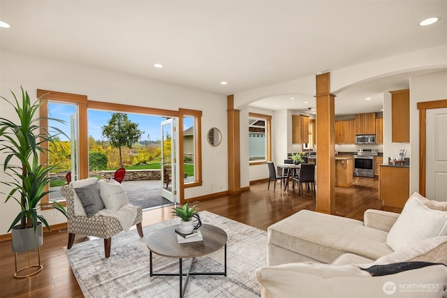 living area with arched walkways, dark wood finished floors, baseboards, ornate columns, and recessed lighting