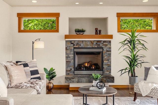 living room featuring a stone fireplace, recessed lighting, wood finished floors, and a wealth of natural light