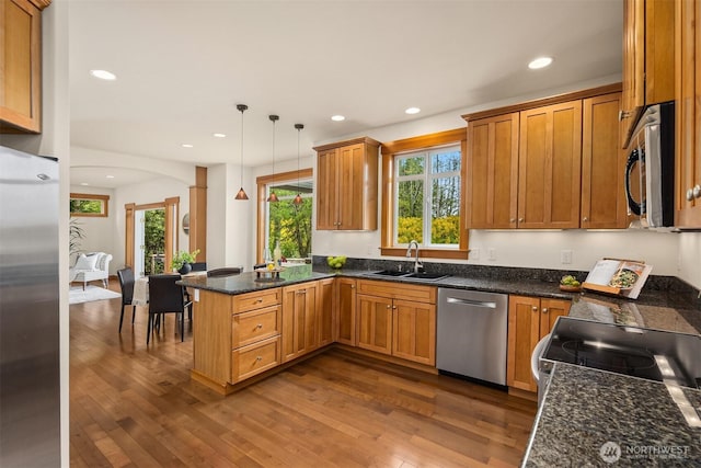 kitchen featuring dark wood-style flooring, a sink, stainless steel appliances, recessed lighting, and a peninsula