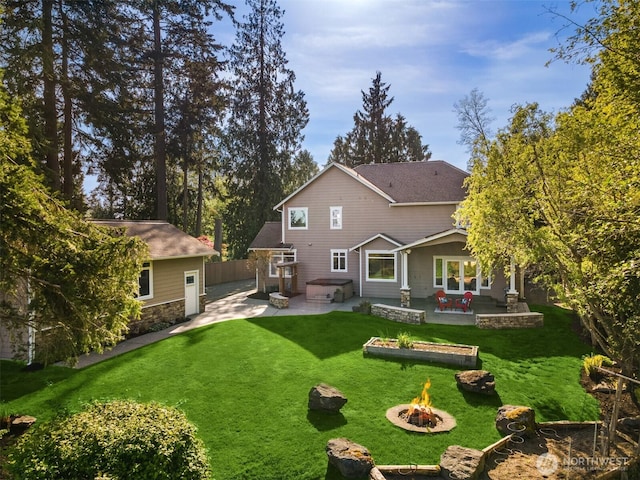rear view of property featuring a lawn, a fire pit, a patio area, and stone siding