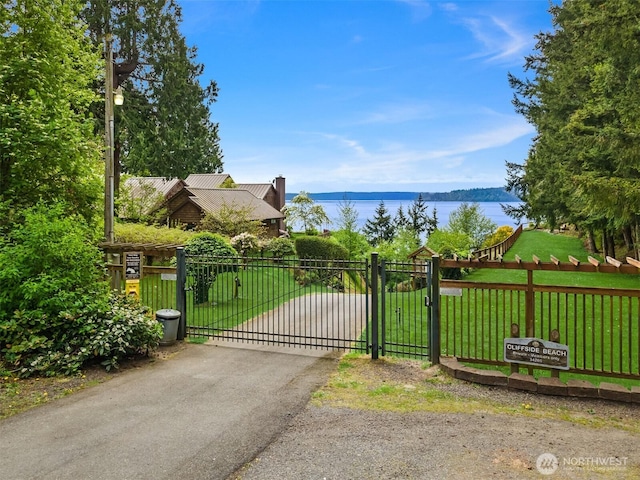 view of gate featuring a water view, fence, and a yard