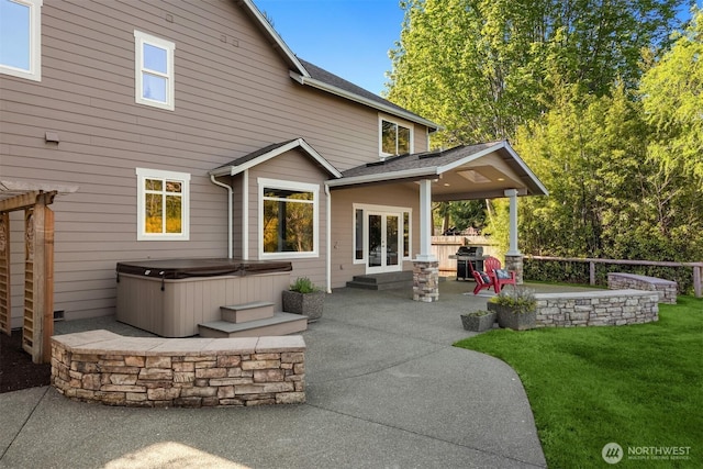 back of house with a yard, a patio, and a hot tub