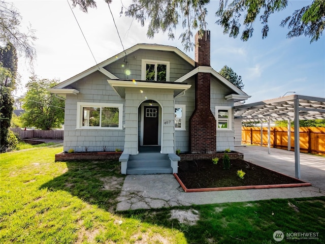 bungalow-style home featuring fence, a chimney, and a front yard