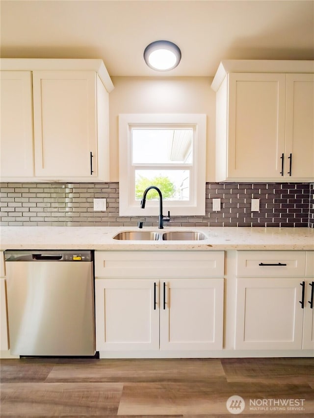 kitchen with light stone countertops, stainless steel dishwasher, white cabinets, and a sink