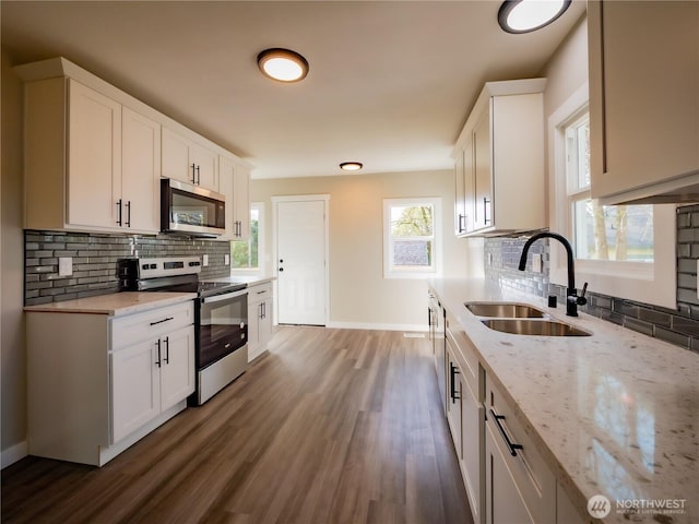 kitchen with baseboards, stainless steel appliances, backsplash, and a sink