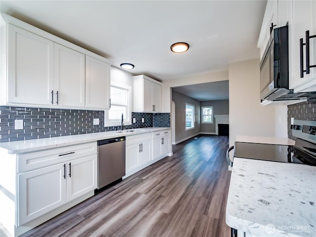 kitchen with tasteful backsplash, white cabinets, a sink, appliances with stainless steel finishes, and wood finished floors
