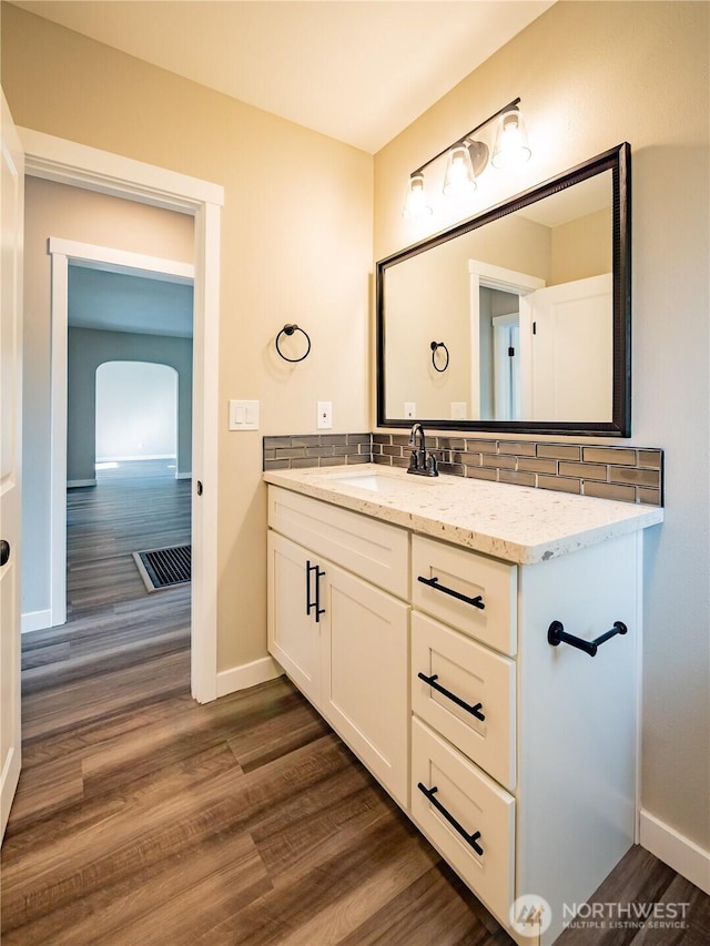 bathroom featuring wood finished floors, tasteful backsplash, vanity, and baseboards