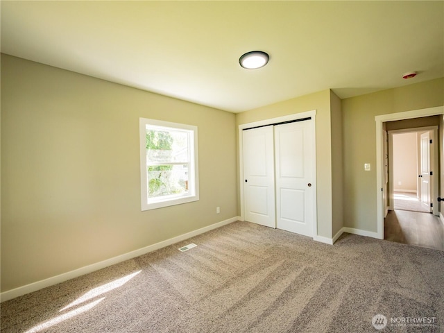 unfurnished bedroom with visible vents, a closet, carpet flooring, and baseboards