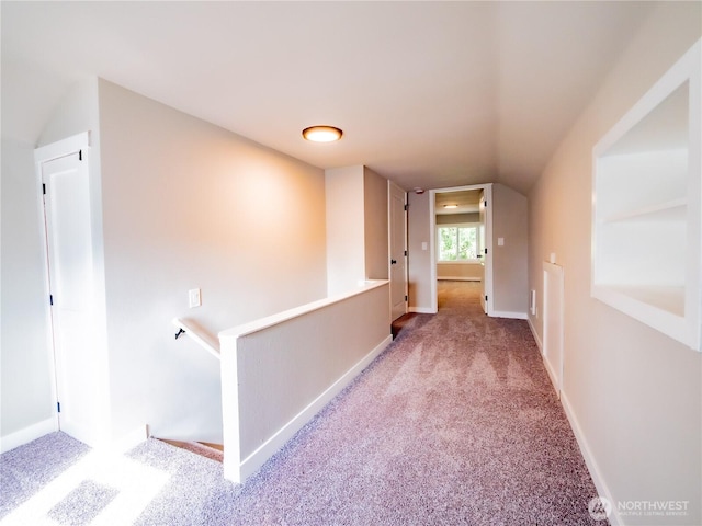 corridor featuring baseboards, an upstairs landing, and carpet flooring