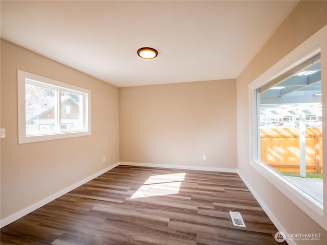 empty room featuring visible vents, wood finished floors, and baseboards