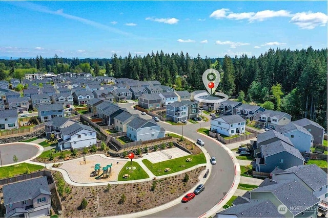 drone / aerial view featuring a wooded view and a residential view