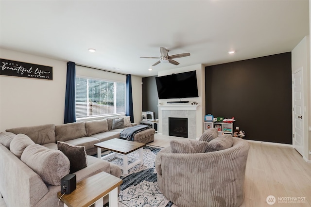 living room with a tiled fireplace, recessed lighting, light wood finished floors, and ceiling fan