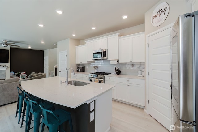 kitchen featuring light wood-type flooring, a sink, appliances with stainless steel finishes, and open floor plan