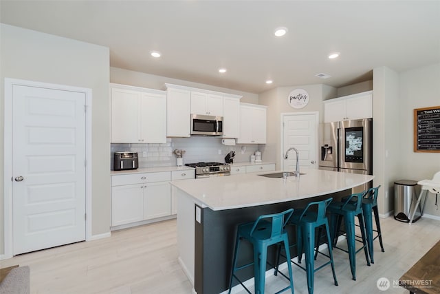 kitchen featuring light wood-style floors, a sink, appliances with stainless steel finishes, and a breakfast bar area