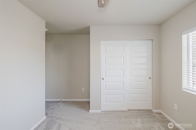 unfurnished bedroom featuring baseboards, light carpet, and multiple windows