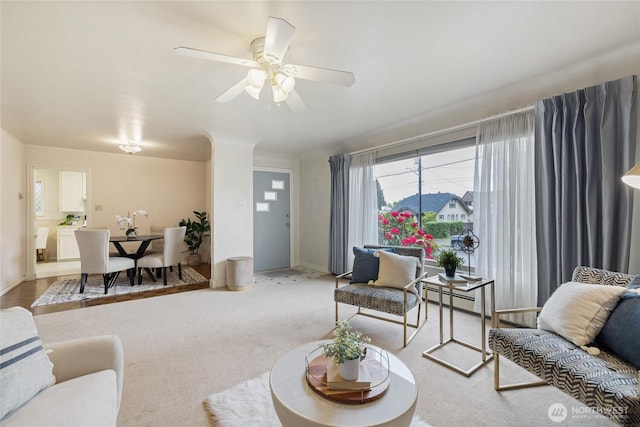 carpeted living area featuring baseboards, a baseboard radiator, and a ceiling fan