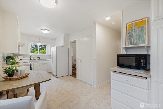 kitchen featuring white appliances, white cabinets, a sink, and light countertops