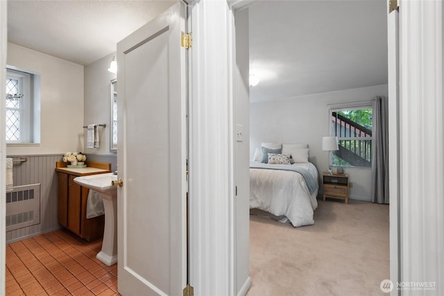 bedroom with radiator heating unit and light carpet