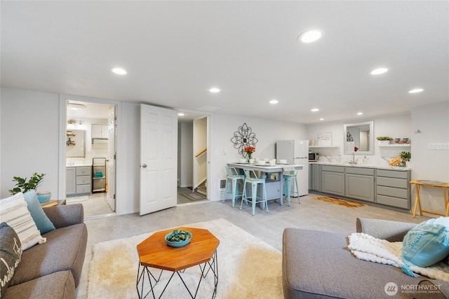 living room with stairs, recessed lighting, and concrete floors