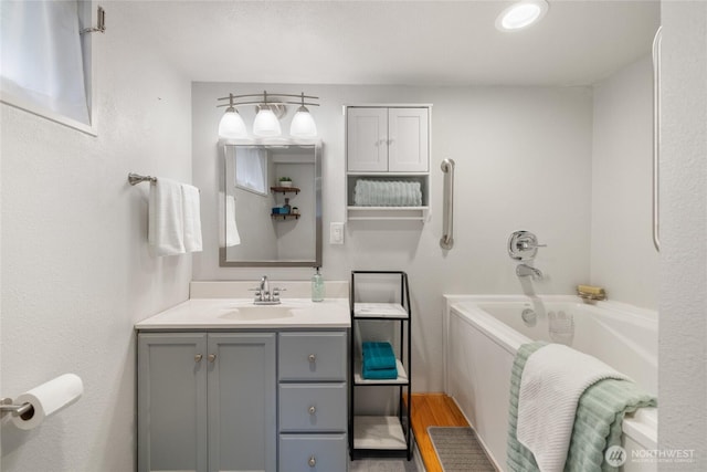 full bathroom with vanity, a garden tub, and wood finished floors
