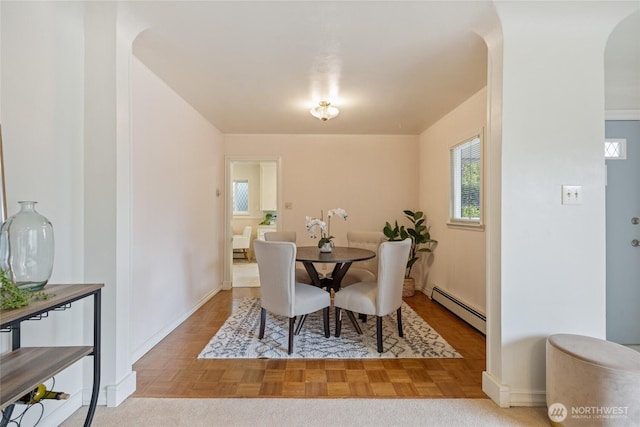 dining space featuring arched walkways, baseboards, and a baseboard radiator