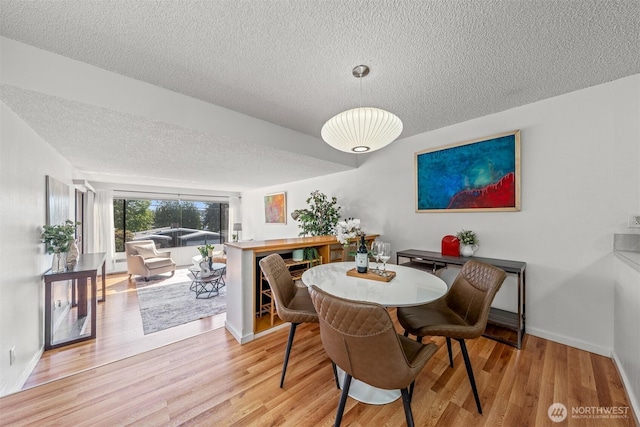 dining room with baseboards, a textured ceiling, and wood finished floors