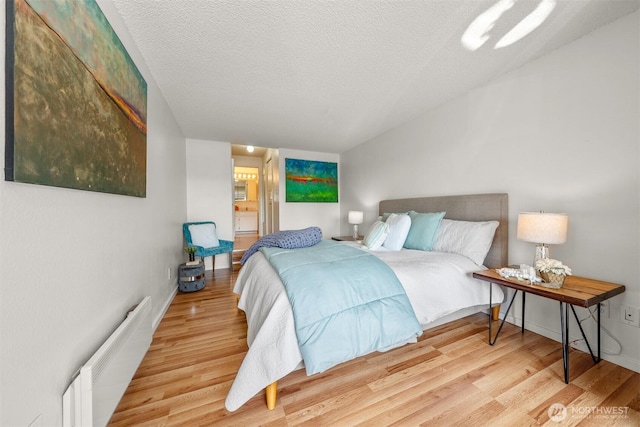 bedroom with radiator, baseboards, a textured ceiling, and wood finished floors
