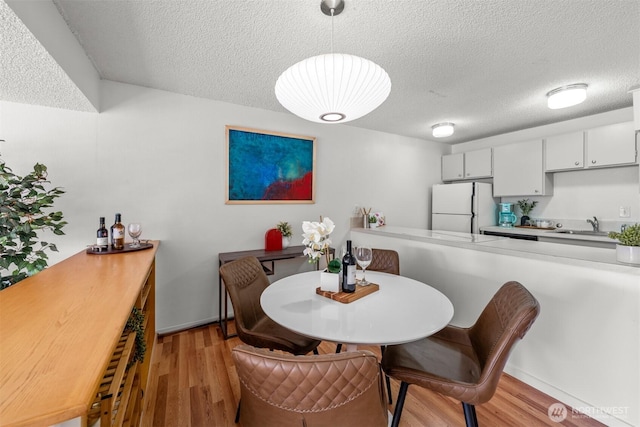 dining space with light wood-style floors and a textured ceiling
