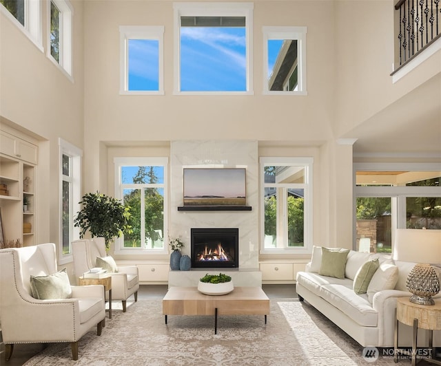 living room featuring a towering ceiling, a premium fireplace, and healthy amount of natural light