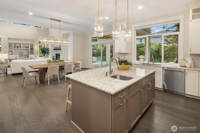 kitchen featuring stainless steel dishwasher, a sink, white cabinets, and recessed lighting