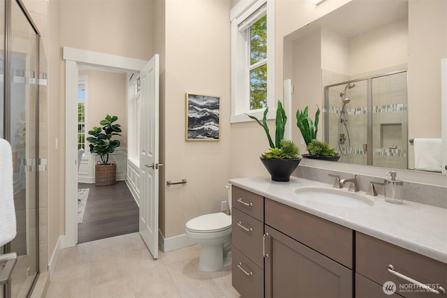 bathroom with a stall shower, vanity, toilet, and baseboards