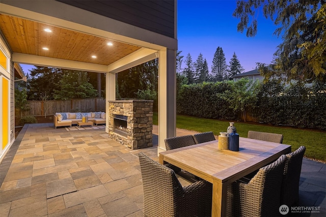 patio terrace at dusk with an outdoor living space with a fireplace and outdoor dining area