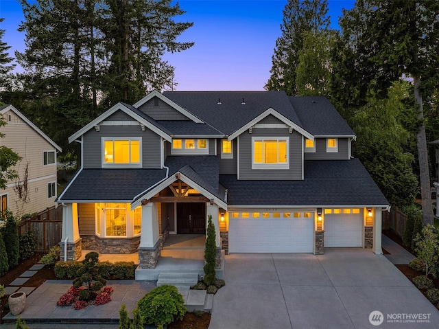 craftsman-style home featuring stone siding, fence, concrete driveway, and roof with shingles