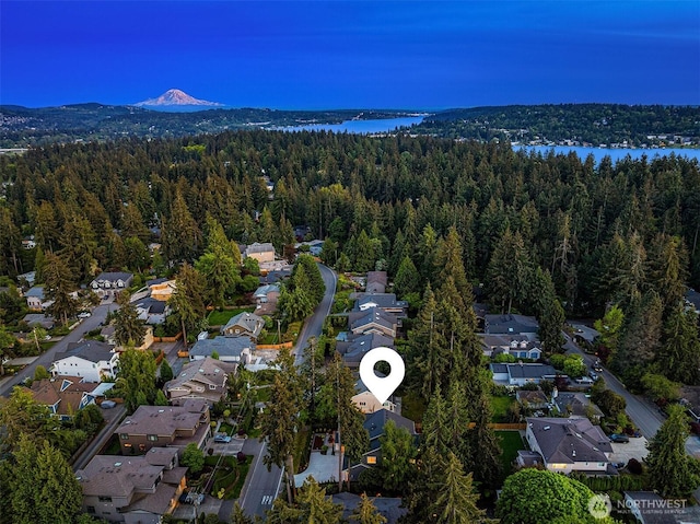aerial overview of property's location featuring a forest, nearby suburban area, and a mountainous background
