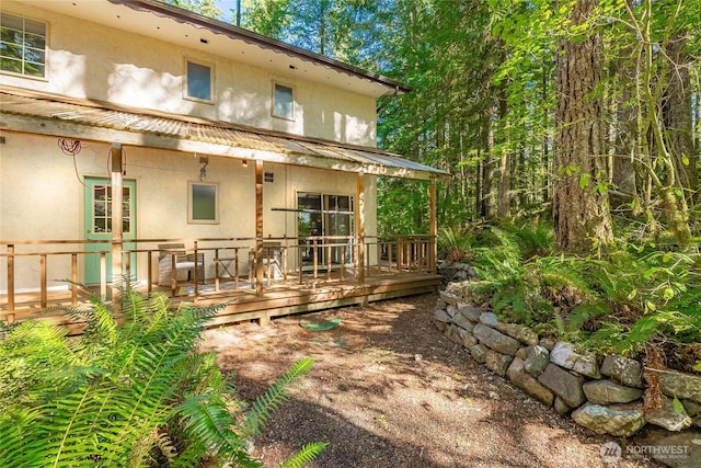 rear view of property featuring a wooden deck and stucco siding