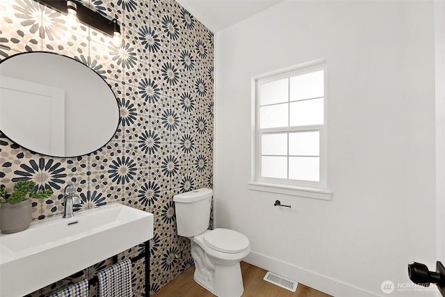 1322 114th St S, Tacoma, WA 98444 - bathroom with a sink, baseboards, wallpapered walls, wood finished floors, and visible vents