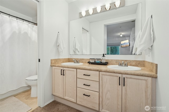 full bath featuring double vanity, a sink, curtained shower, and toilet